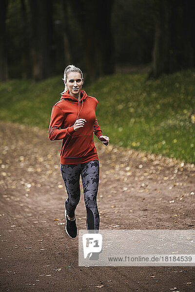 Smiling sportswoman running on footpath
