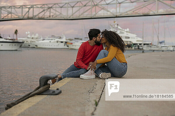 Romantisches junges Paar küsst sich bei Sonnenuntergang auf der Promenade