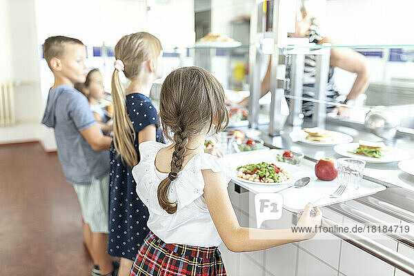 Students standing side by side taking lunch in school cafeteria