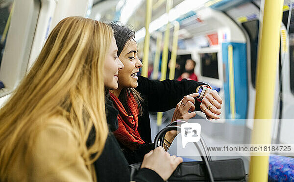 UK,  London,  Two young women in the underground looking at smart watch