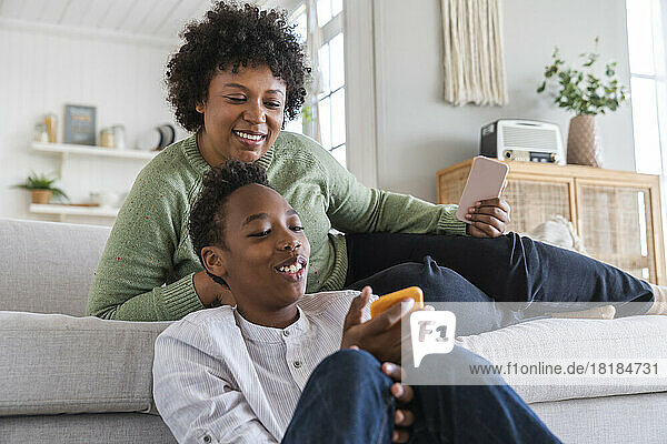 Happy boy sharing mobile phone with mother at home