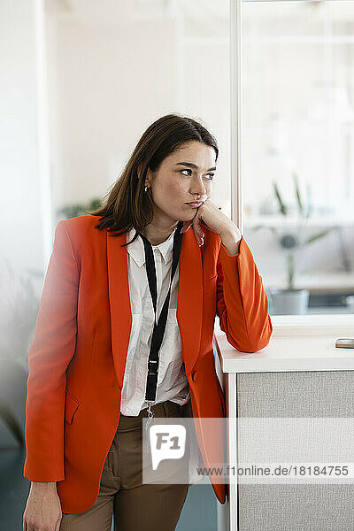 Sad businesswoman standing by cabinet in office