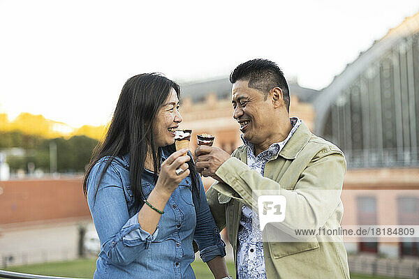 Happy mature couple having ice cream cone together on weekend
