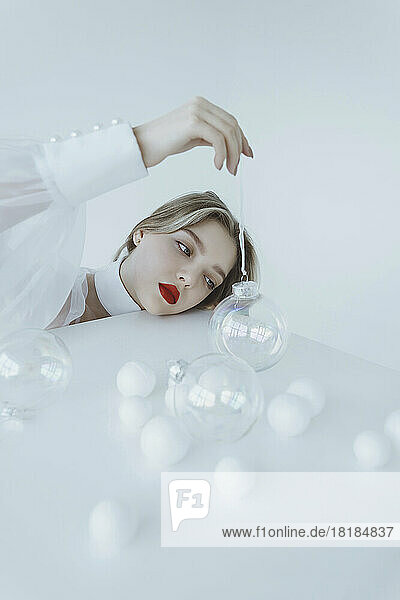 Girl holding transparent Christmas ball on white table