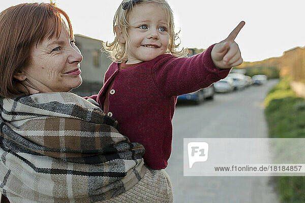 Lächelnde Frau mit Enkelin gestikuliert auf Fußweg