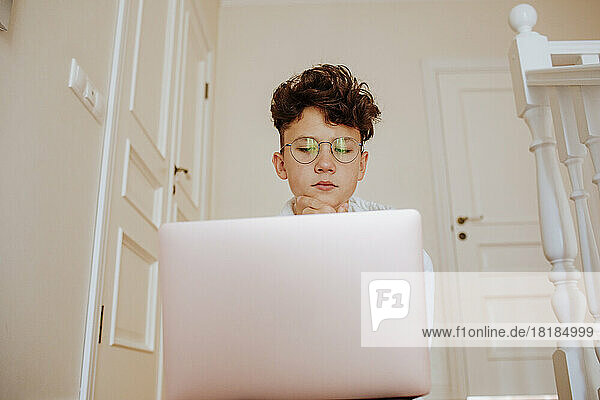 Junge sitzt zu Hause vor Laptop