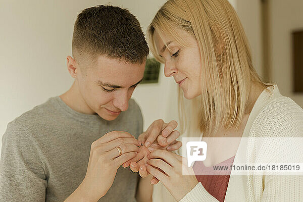 Young man removing splinter from woman's hand at home