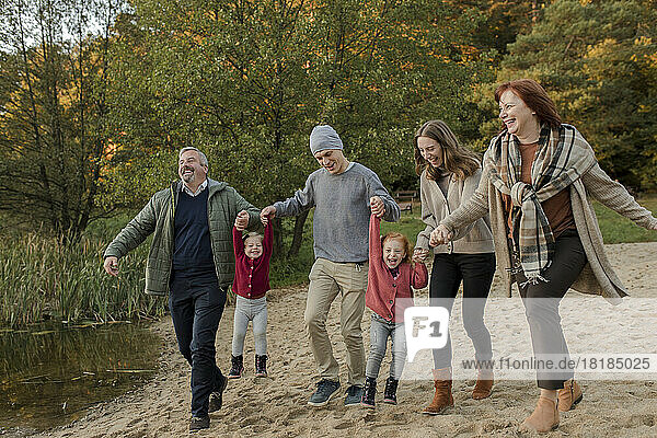 Verspielte Familie verbringt ihre Freizeit miteinander beim Spazierengehen im Sand