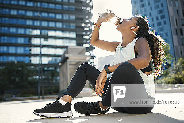 Thirsty woman drinking water on sunny day
