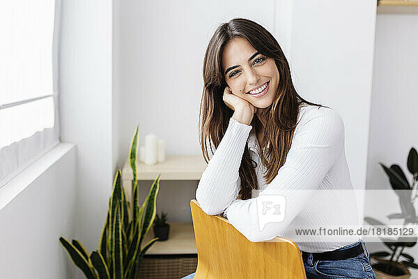 Happy beautiful woman sitting on chair at home
