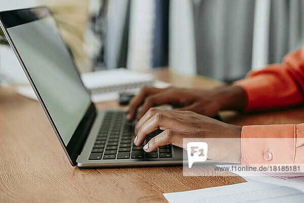 Hands of young businesswoman using laptop at desk