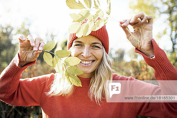 Happy woman holding sprigs on sunny day