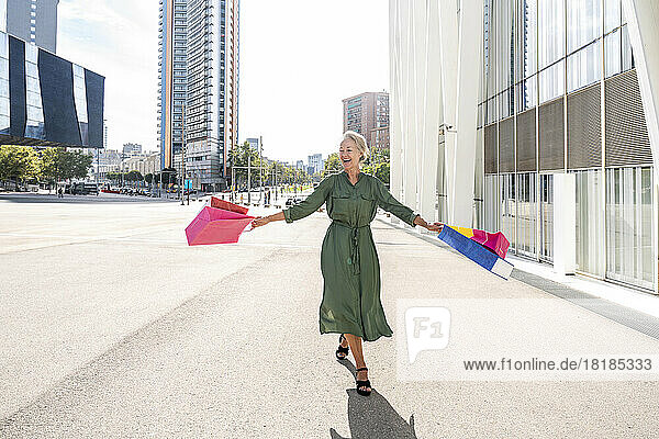 Happy woman carrying shopping bags in city
