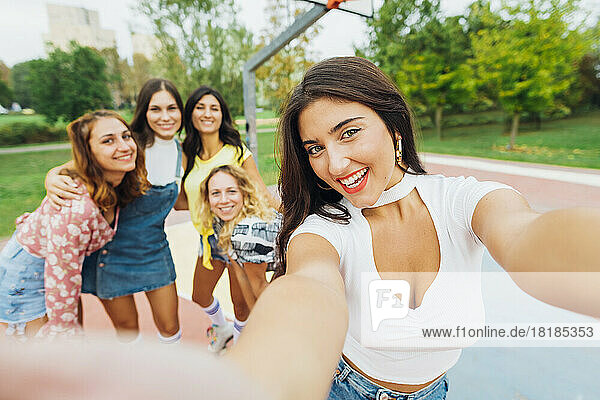 Happy woman taking selfie with friends at sports court