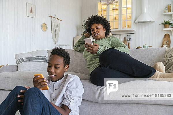 Mutter und Sohn nutzen zu Hause Smartphones