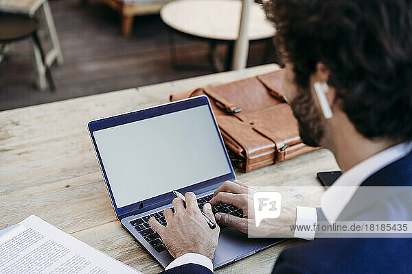 Businessman typing on laptop sitting at table in cafe