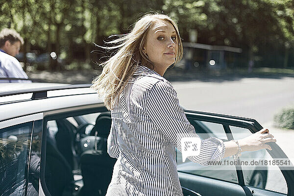 Germany  Duesseldorf  Young woman getting in to car