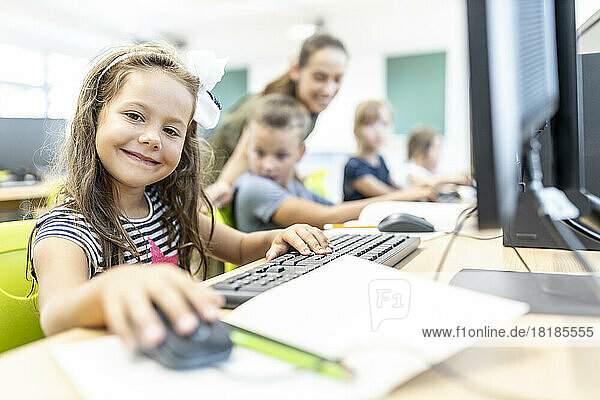 Smiling student sitting in computer class at school