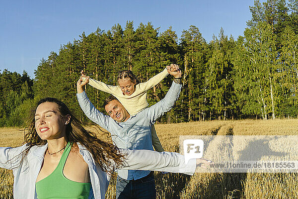 Happy family enjoying together in field on sunny day