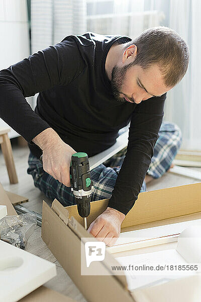 Man using drill machine on table at home