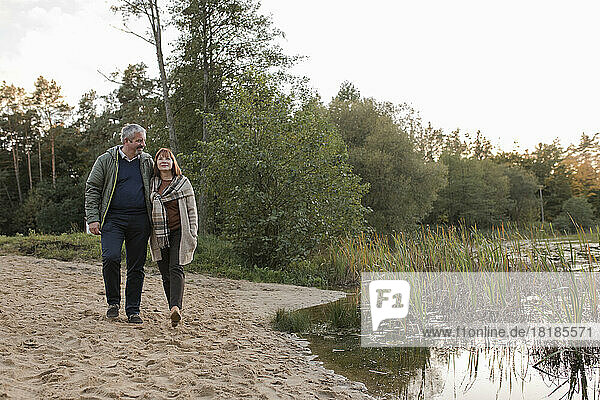 Mann und Frau gehen gemeinsam im Sand am See spazieren
