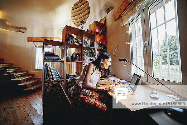 Reife Frau sitzt mit Laptop am Tisch zu Hause