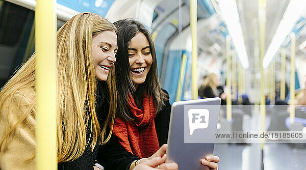 UK,  London,  Two young women in the underground using digital tablet