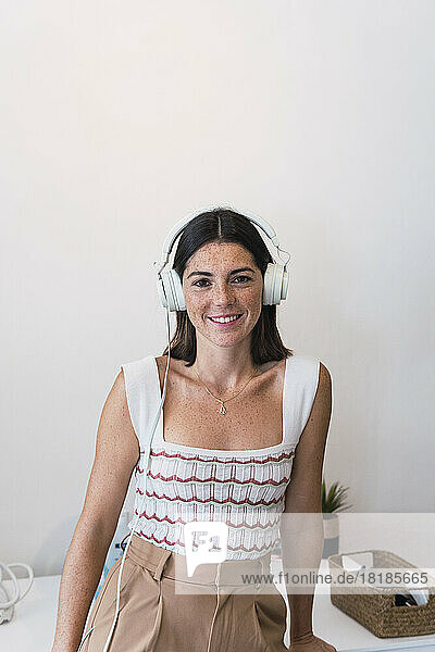 Happy young businesswoman wearing headphones listening to music in office