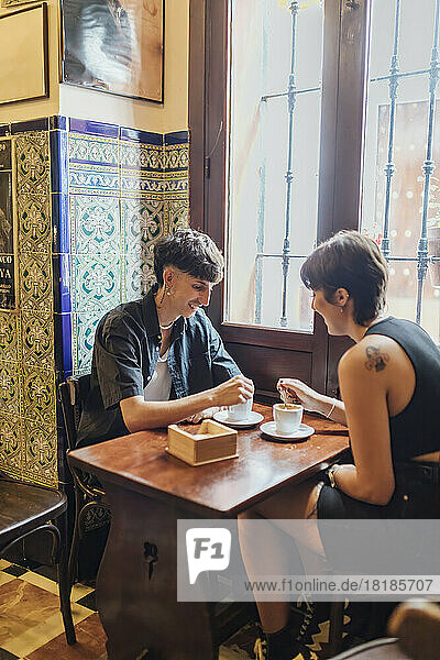 Glückliches junges Paar rührt Kaffee im Café