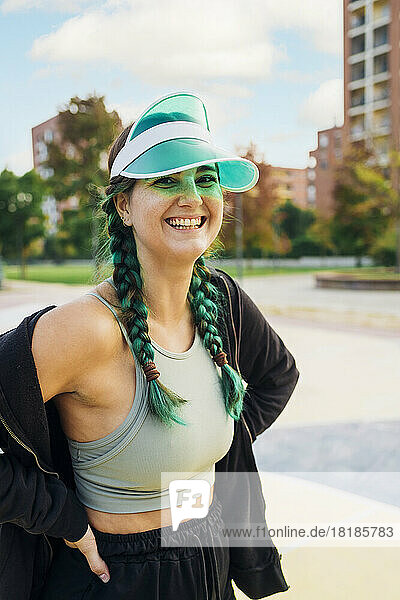 Happy young woman wearing sun visor at sports court