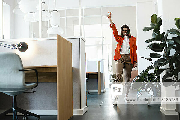 Happy businesswoman gesturing peace in office