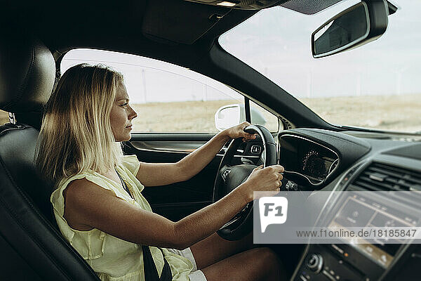 Blonde Frau mit Lenkrad sitzt im Auto