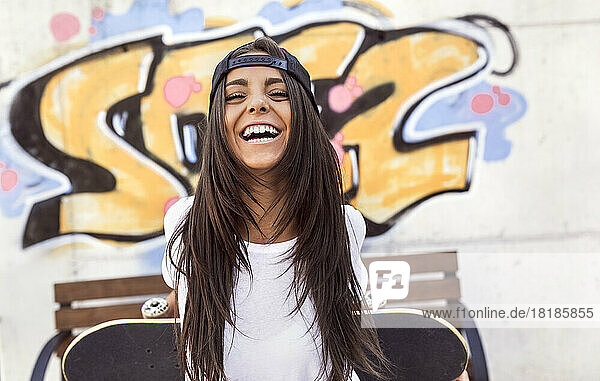 Laughing young woman holding skateboard