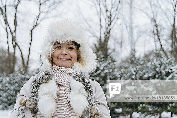 Smiling woman wearing fur hat standing in snow