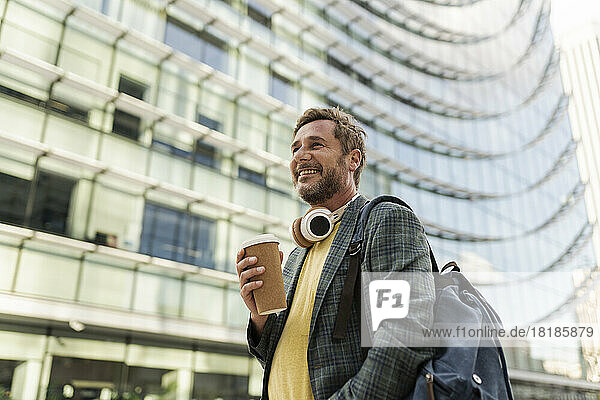 Smiling man holding disposable cup in city