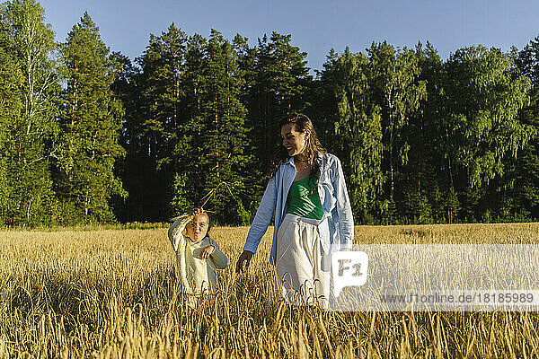 Happy woman with daughter walking on field