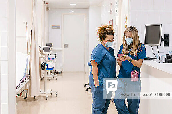 Mature nurse discussing with colleague using smart phone at medical clinic