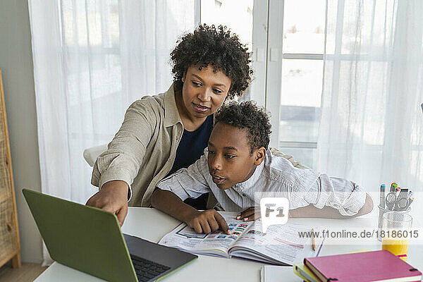 Mutter und Junge nutzen Laptop und lernen zu Hause