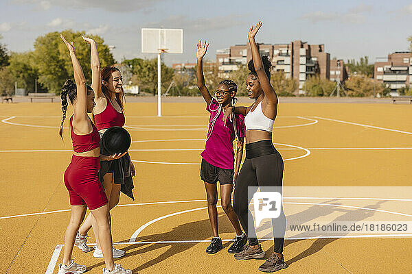 Young women standing with hands raised in sports court