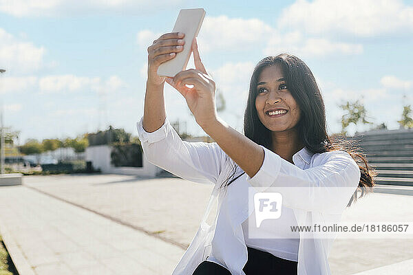 Happy young woman taking selfie through smart phone