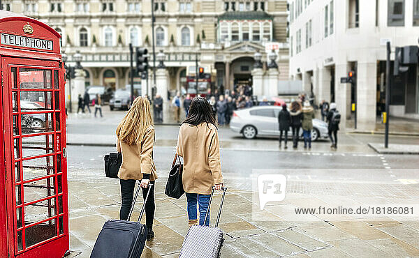 UK  London  Two friends exploring the city  arriving with trolley bags