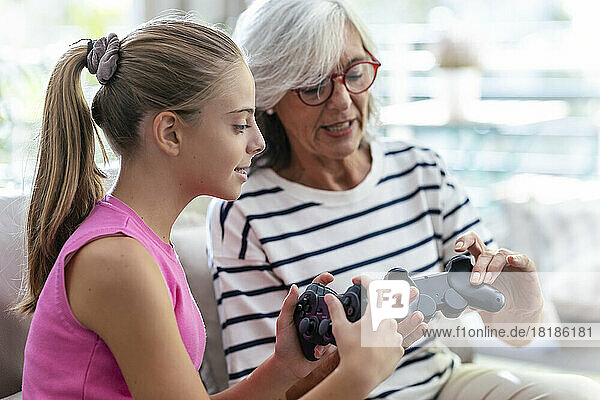 Grandmother and granddaughter talking to each other holding joysticks at home