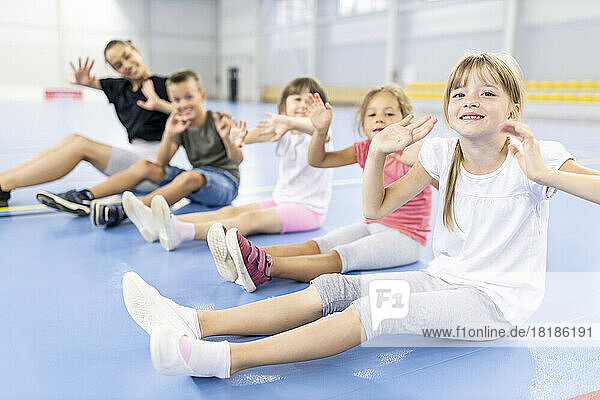 Students and teacher doing exercise sitting together at school sports court