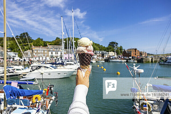 UK  England  Padstow  Personal perspective of woman holding ice cream against town harbor