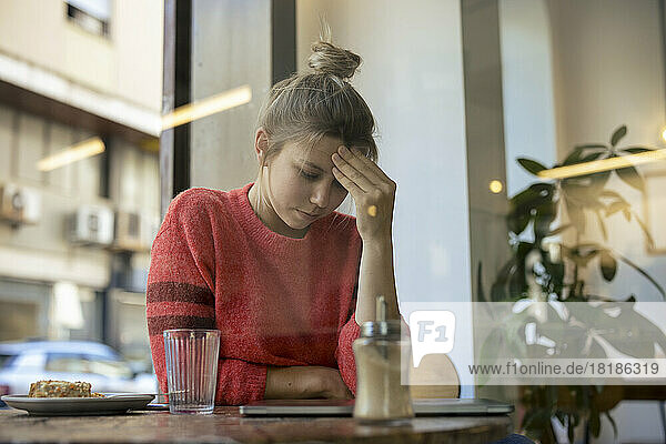 Tired freelancer sitting at table in cafe