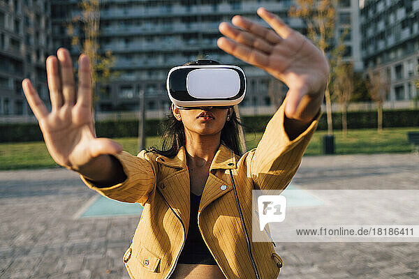 Junge Frau gestikuliert an einem sonnigen Tag mit einem Virtual-Reality-Simulator