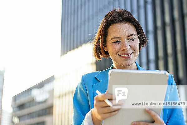 Lächelnde Geschäftsfrau blickt auf Tablet-PC