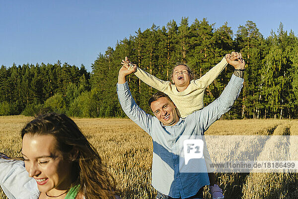 Smiling man playing with family in field on sunny day