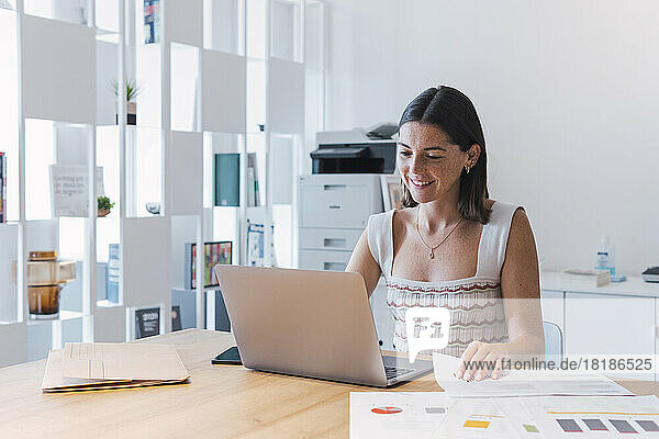 Smiling businesswoman using laptop in office