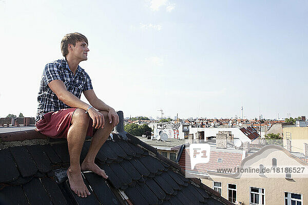 Deutschland  Berlin  Mann sitzt auf dem Dach